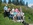 9 Personen und 2 Hunde auf einem Gruppenbild auf Parkbank im Grünen..
